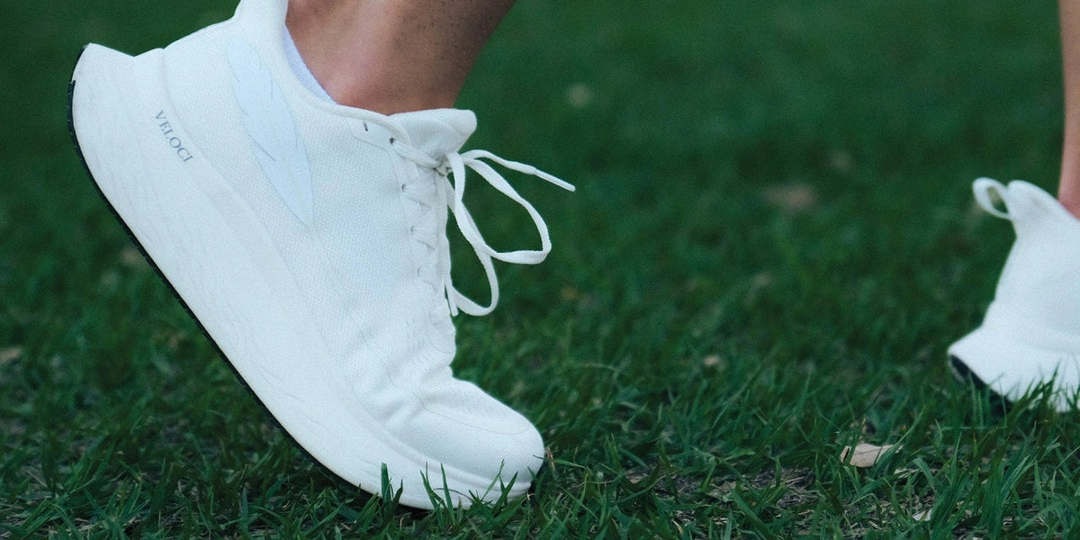 Veloci Ascent in white mid stride on grass, close up of the naturally shaped toe box