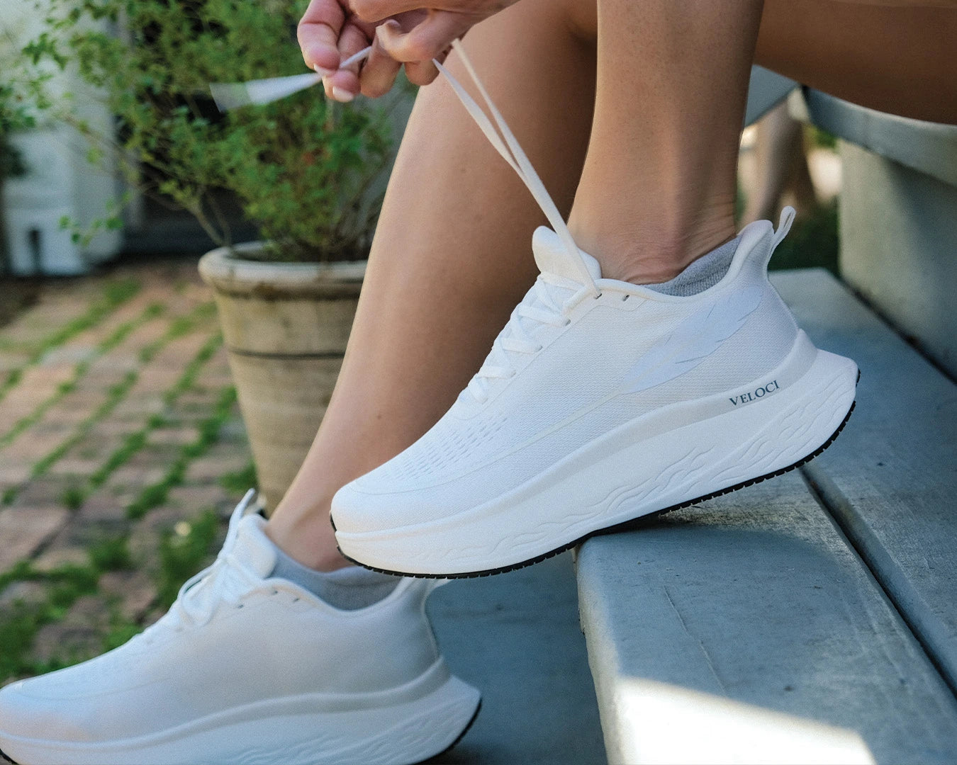 Veloci Ascent running shoe in white with white midsole, outdoor side profile showing the wide toe box, supportive foam, and breathable upper